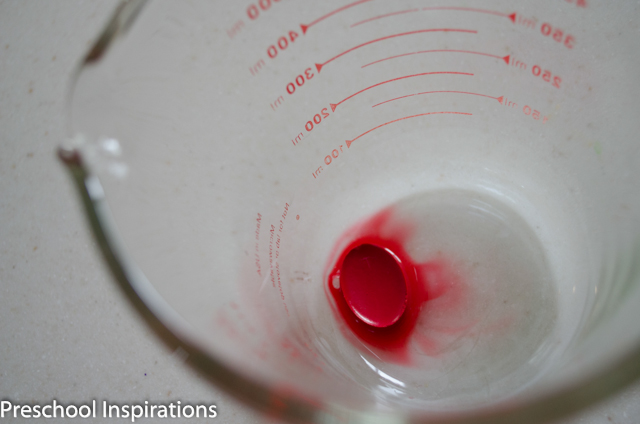 a red watercolor cake in a small amount of water at the bottom of a measuring cup