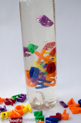 The bottom of an alphabet discovery bottle surrounded by alphabet letter beads