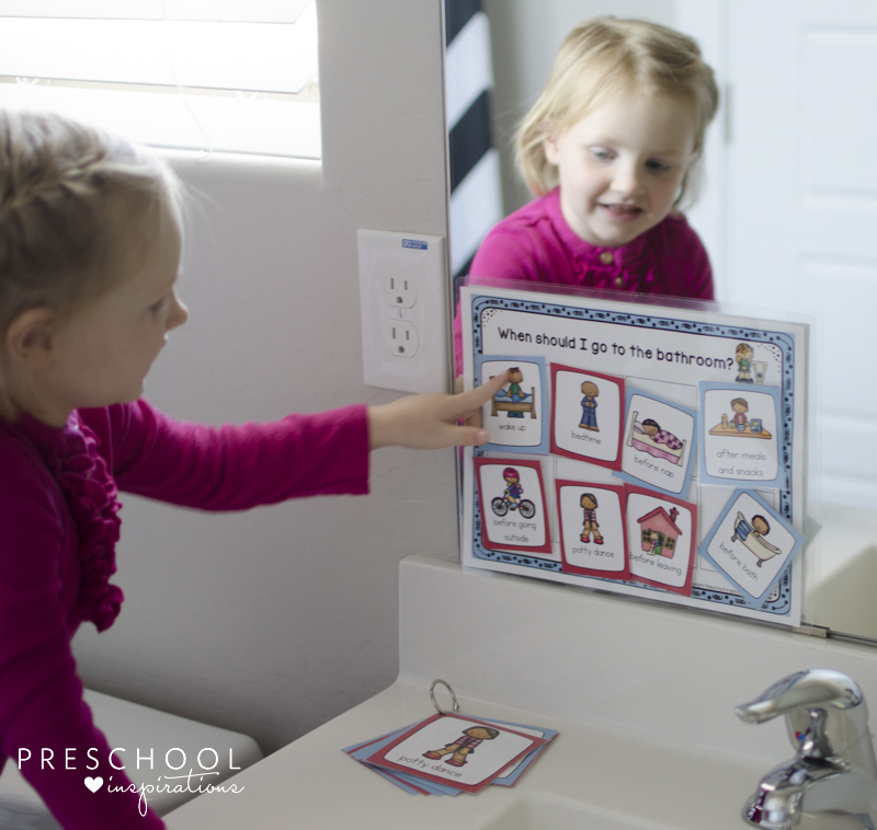 a child uses a potty training chart and visual schedule in the bathroom