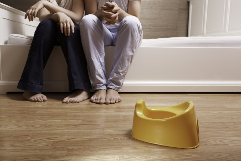 Young parents are sitting on the bed and thinking how to teach kid to potty train
