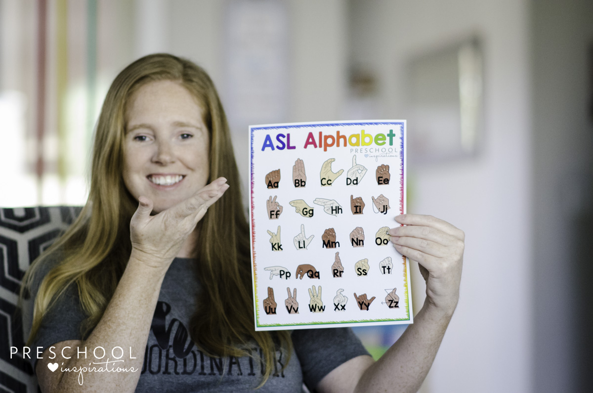 teacher holding an ASL Alphabet poster