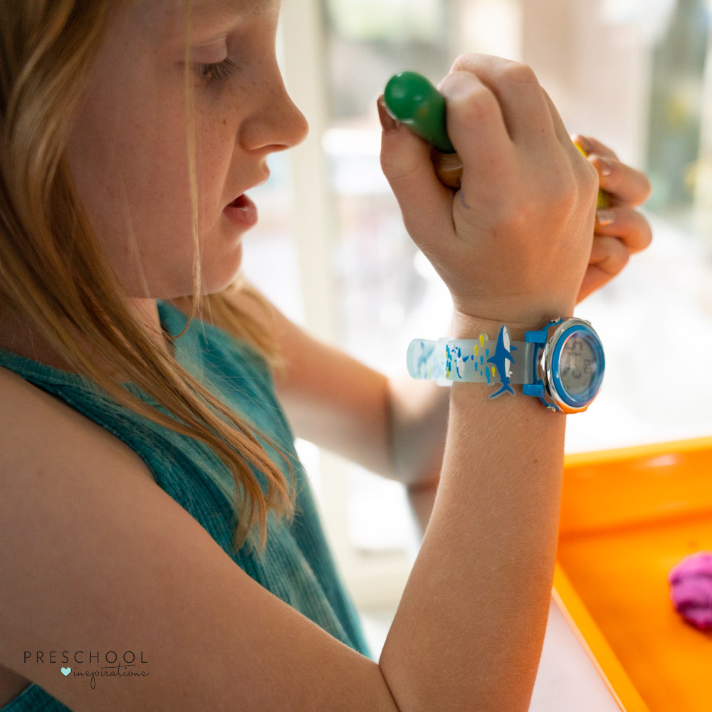 Child with digital watch holding a playdough roller