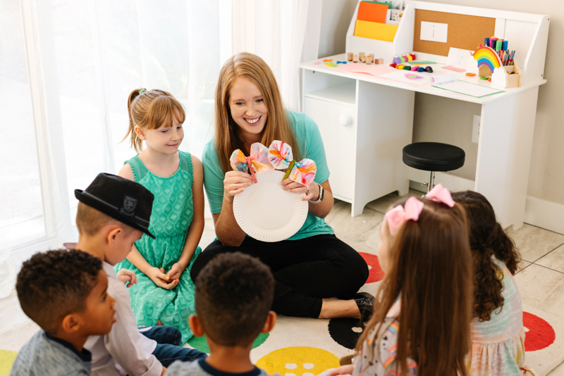 Teacher holding butterfly puppets with children during circle time